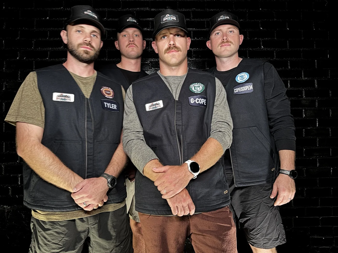 All four Hunters standing together in front of a black brick wall